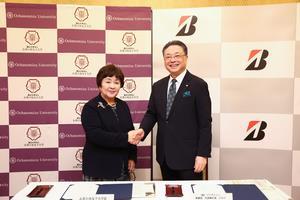 University President Kimiko Murofushi and Bridgestone CEO Masaaki Tsuya shake hands after signing the agreement