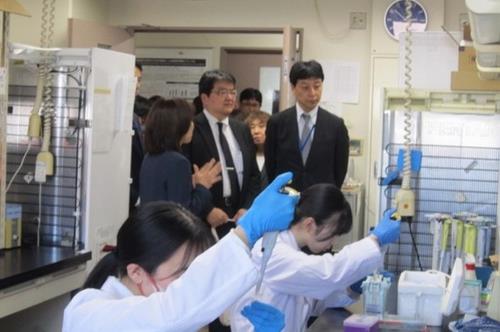 市育代教授研究室にて、学生が実験を行っている様子を視察する 先﨑審議官と村尾国立大学法人支援課長(中央)